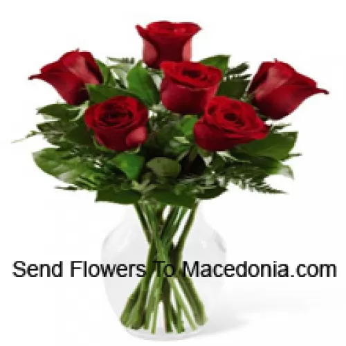7 roses rouges avec quelques fougères dans un vase en verre